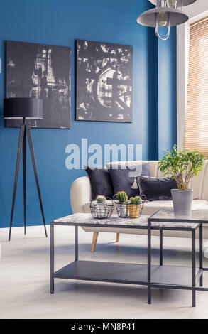 Table basse industrielle noir avec dessus marbre dans un salon élégant avec l'intérieur noir art sur les murs bleu Banque D'Images