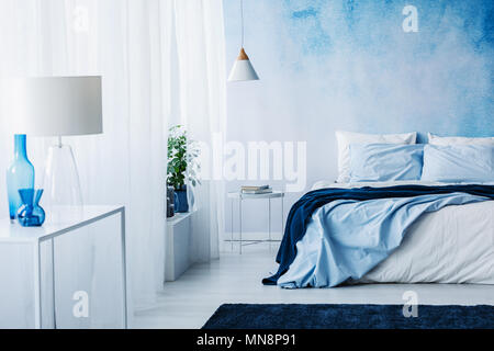 Chambre détente intérieur avec des décorations blanc et bleu, d'un lit double et de papier peint Banque D'Images