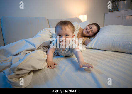 Cute smiling baby boy crawling on lit vers la caméra Banque D'Images