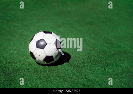 Vieux, sale tattered ballon de soccer sur fond d'herbe verte. Noir et blanc classique traditionnelle boule de football sur terrain vert de la formation du stade Banque D'Images