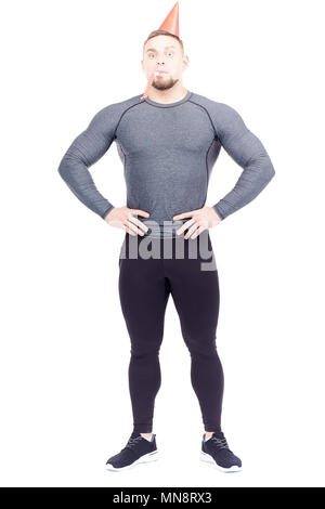 Studio portrait of fit man en sports de vêtements wearing party hat et souffle dans la corne Banque D'Images