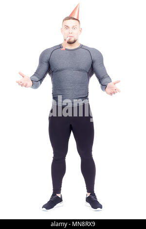 Studio portrait of fit man en sports de vêtements wearing party hat et souffle dans la corne Banque D'Images