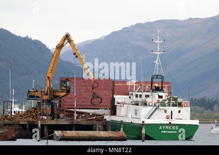 Un Ayress Portsmouth bateau amarré à la Sainte Loch, Firth of Clyde, en Écosse, au Royaume-Uni d'être chargé de grumes coupées par un Multidocker. Banque D'Images