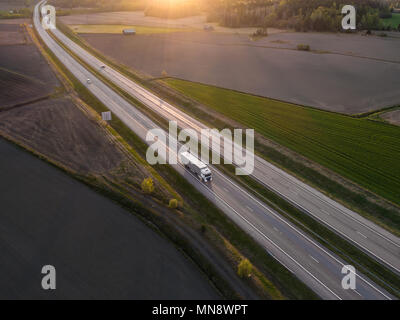 Vue aérienne de l'autoroute avec la conduite de camions de marchandises d'au coucher du soleil du printemps Banque D'Images