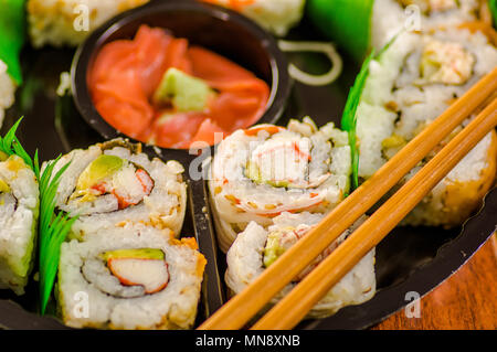 Close up of selective focus de grand ensemble de délicieux rouleaux de sushi japonais sur une plaque en plastique noir Banque D'Images