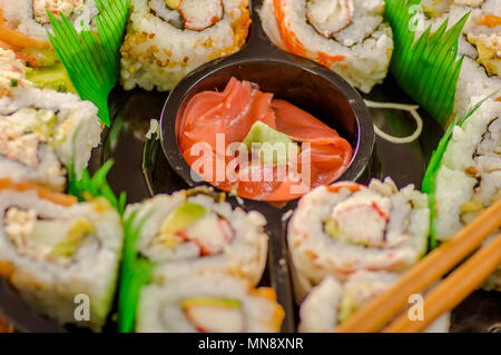 Close up of selective focus de grand ensemble de délicieux rouleaux de sushi japonais sur une plaque en plastique noir Banque D'Images