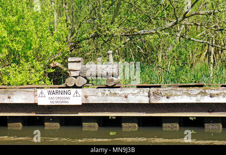 Un modèle naïf train en bois par un gazoduc traversant sur la rivière Bure près de Belaugh, Norfolk, Angleterre, Royaume-Uni, Europe. Banque D'Images