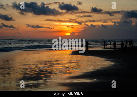 Plage de Berawa (Pantai Berawa) au coucher du soleil. Silhouettes de promeneurs sur. Canggu, Bali, Indonésie. Banque D'Images