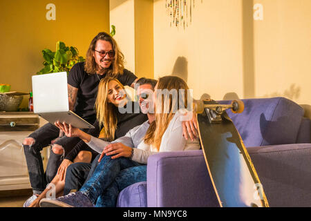 Le travail d'équipe d'amis young caucasian travaillant ensemble pour trendy concept activité. lapto, skateboard et quatre hommes et femmes à l'aide d'ordinateur portable s'amusant Banque D'Images