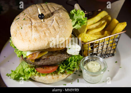 Un hamburger accompagné de frites. Le burger dispose d''un oignon ring, œuf frit et salade. Banque D'Images