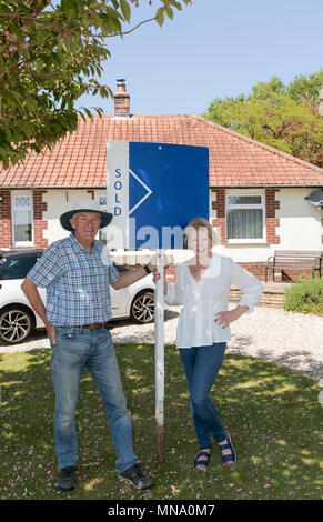 Couple avec un signe extérieur de leur maison vendue Banque D'Images