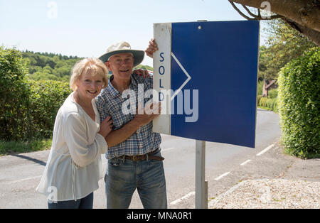 Couple avec un signe extérieur de leur maison vendue Banque D'Images