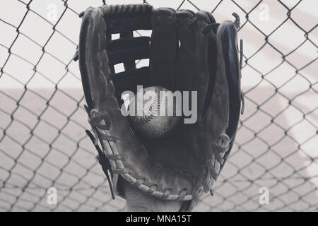 Le sport américain de baseball balle de gros plan montre en noir et blanc avec des gants. Clôture de l'étang en arrière-plan Banque D'Images