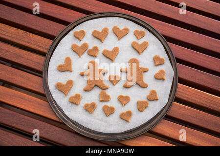 Gingerbread couple entouré de cœurs en plaque sur la table Banque D'Images