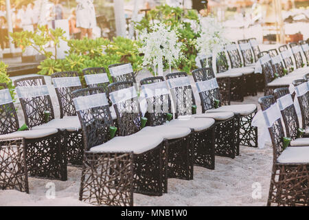 Un groupe de chaises en bois tissu noir avec sash blanc décoration intérieure et extérieure des pétales de rose pour salle de mariage de plage sur le sable blanc Banque D'Images