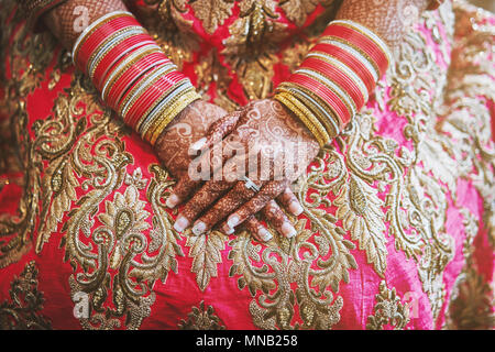 Le gros plan de la mariée indienne avec de beaux saree rose montrant mehndi (henné) part avec beaucoup de paillettes bracelets bangles () sur son poignet Banque D'Images