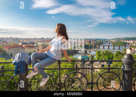 Panorama de la ville de Prague, la Vltava avec ses nombreux ponts et une belle jeune femme assise sur une clôture, profiter du soleil et de la vue. Banque D'Images