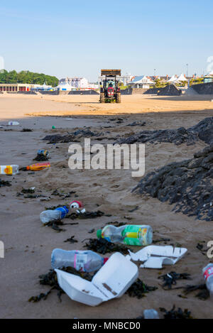 Déchets de premier plan sur la plage de sable tranquille station touristique au début par un beau matin d'été ensoleillé en cours de nettoyage par tracteur avec fond surf rake. Banque D'Images