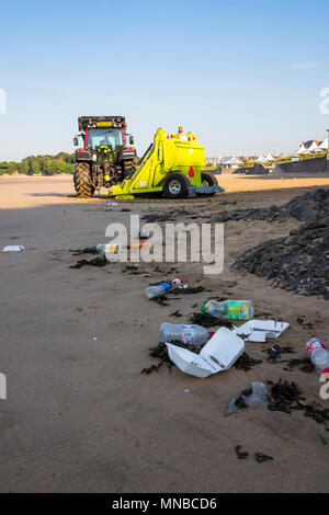 Déchets de premier plan sur la plage de sable tranquille station touristique au début par un beau matin d'été ensoleillé en cours de nettoyage par tracteur avec fond surf rake. Banque D'Images