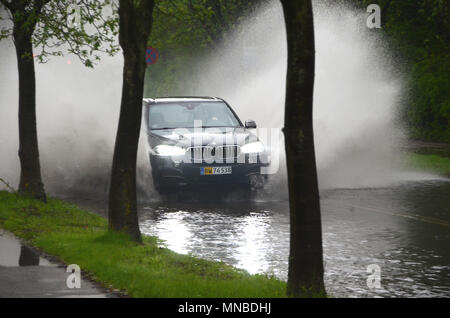 Sonderborg, Danemark - 10 mai 2018 : une voiture éclabousse l'eau creux sur une route qui est inondé après une forte pluie. . Banque D'Images