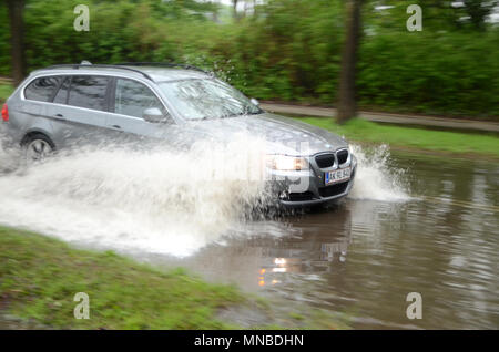 Sonderborg, Danemark - 10 mai 2018 : une voiture éclabousse l'eau creux sur une route qui est inondé après une forte pluie. . Banque D'Images