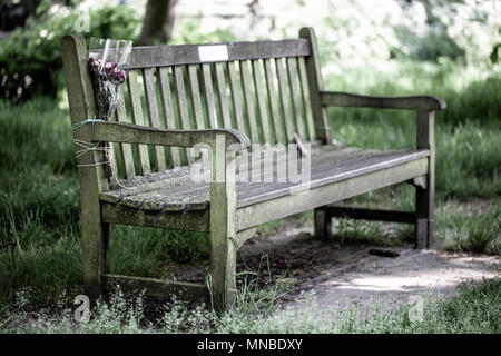 Memorail en bois banc dans le parc avec bouquet de fleurs noué sur avec string Banque D'Images