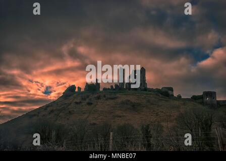 Le soleil se lève derrière les ruines du château de Corfe, dans le Dorset, UK Banque D'Images