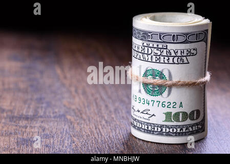 Libre, macro de billets en dollars américains roulé sur le côté droit. Fond de bois. Banque D'Images
