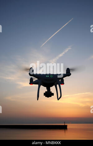 Drone télécommandé équipé de photo aérienne et vidéo planant dans l'air et le coucher du soleil Banque D'Images