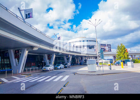 MINSK, BELARUS - 01 MAI 2018 : vue extérieure des voitures garées et la circulation à l'entrée du bâtiment de l'aéroport de Minsk dans un jour nuageux avec une tour de contrôle derrière Banque D'Images