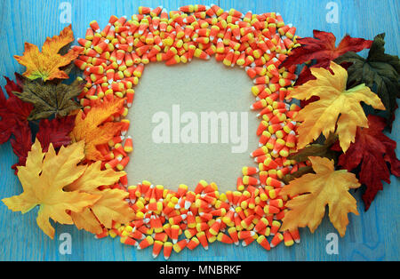 Image de candy corns avec feuilles d'automne. Entourant les bords du cadre est un fond rustique en bois vert. Concept d'automne sale sign/ partie invite. Banque D'Images