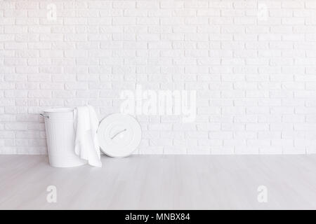 Panier à linge blanc debout dans cette chambre spacieuse avec parquet et mur de brique de lumière Banque D'Images