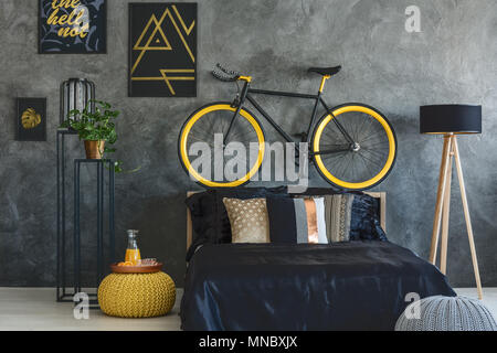 Gris branché chambre avec lit, vélo et affiches de murs Banque D'Images