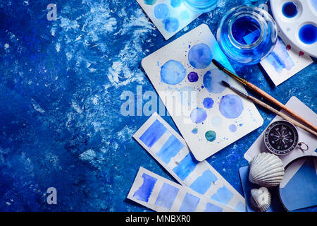 Tons de bleu de travail de l'artiste avec vue sur la mer, aquarelle, croquis, palettes pinceaux et pots de l'eau, de coquillages et de la boussole. La mer sur un concept de peinture marine bl Banque D'Images