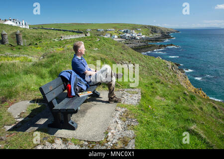 Le chemin des hautes terres du Sud, assis sur un banc au-dessus des falaises à Portpatrick. Walker se détendre en profitant de la vue sur la mer d'Irlande à l'Irlande Banque D'Images