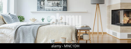 Chambre blanche élégante avec des éléments de l'intérieur gris, une cheminée moderne et de meubles en bois Banque D'Images