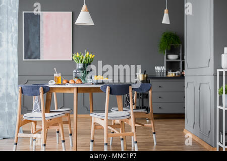 Salle à manger gris avec intérieur peinture rose et bleu, table en bois et une commode Banque D'Images