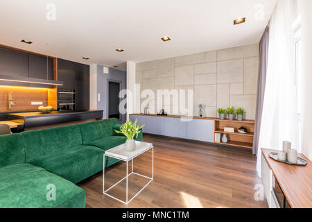 Les tulipes sur table blanc à côté d'un coin vert canapé dans cet appartement spacieux intérieur avec armoire en bois Banque D'Images