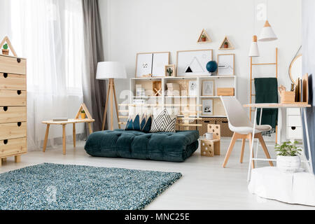 Coussins à motifs vert entre futon sur table en bois et chaise blanche dans la salle de jeu de l'intérieur Banque D'Images