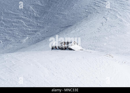 Cabane de montagne, en vaste champ de neige non suivies avec crêtes ondulées formé par le vent sur la neige d'emballage journée ensoleillée en hiver Banque D'Images