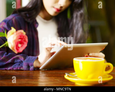 Young Asian woman using digital tablet in coffee shop Banque D'Images