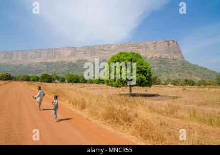 Deux inconnus qui se promenaient sur le chemin de terre à l'arrière avec un arbre et la montagne Banque D'Images