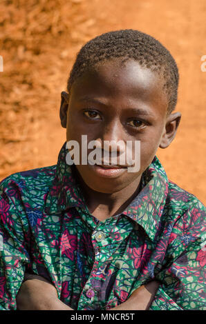 Kindia, Guinée - 28 décembre 2013 : Portrait of African boy non identifiés avec route de terre en arrière-plan Banque D'Images