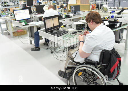 Travailleur handicapé dans un fauteuil roulant l'assemblage de composants électroniques dans une usine moderne sur le lieu de travail Banque D'Images