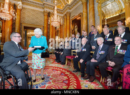 La reine Elizabeth II est donné un livre par le Major Peter Norton GC, qui rappelle les exploits accomplis par les vingt-cinq récipiendaires de la Croix de Victoria et George médailles, à la suite d'une photo de groupe prise au palais de Buckingham à Londres. Banque D'Images