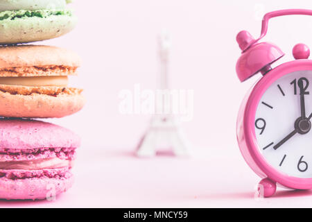 Pile de macarons colorés, petits réveil et miniature de la Tour Eiffel en arrière-plan un minimum de concept créatif. Banque D'Images