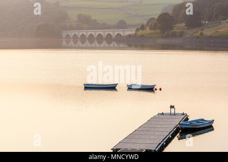 Jetty et trois barques au crépuscule, sur l'eau à Ladybower Reservoir. Ashopton viaduc est dans la distance. Peak District, Derbyshire, Angleterre, RU Banque D'Images