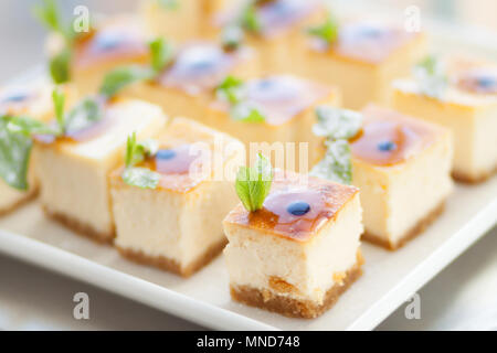 Appétissant gâteau au fromage avec des feuilles de menthe. Tranches de délicieux dessert sur assiette blanche. Banque D'Images
