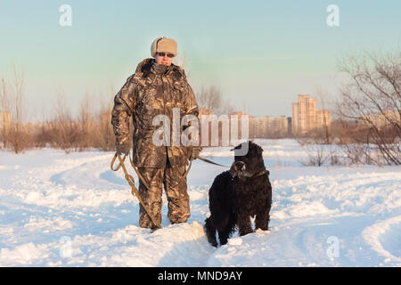 Black grand basset griffon vendéen chien avec son maître sur un marche sur neige hiver Banque D'Images