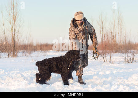 Black grand basset griffon vendéen chien avec son maître sur un marche sur neige hiver Banque D'Images